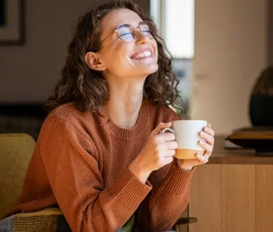 Happy lady smiling holding a cup of tea.