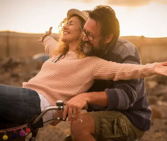 Happy couple riding a bike together.